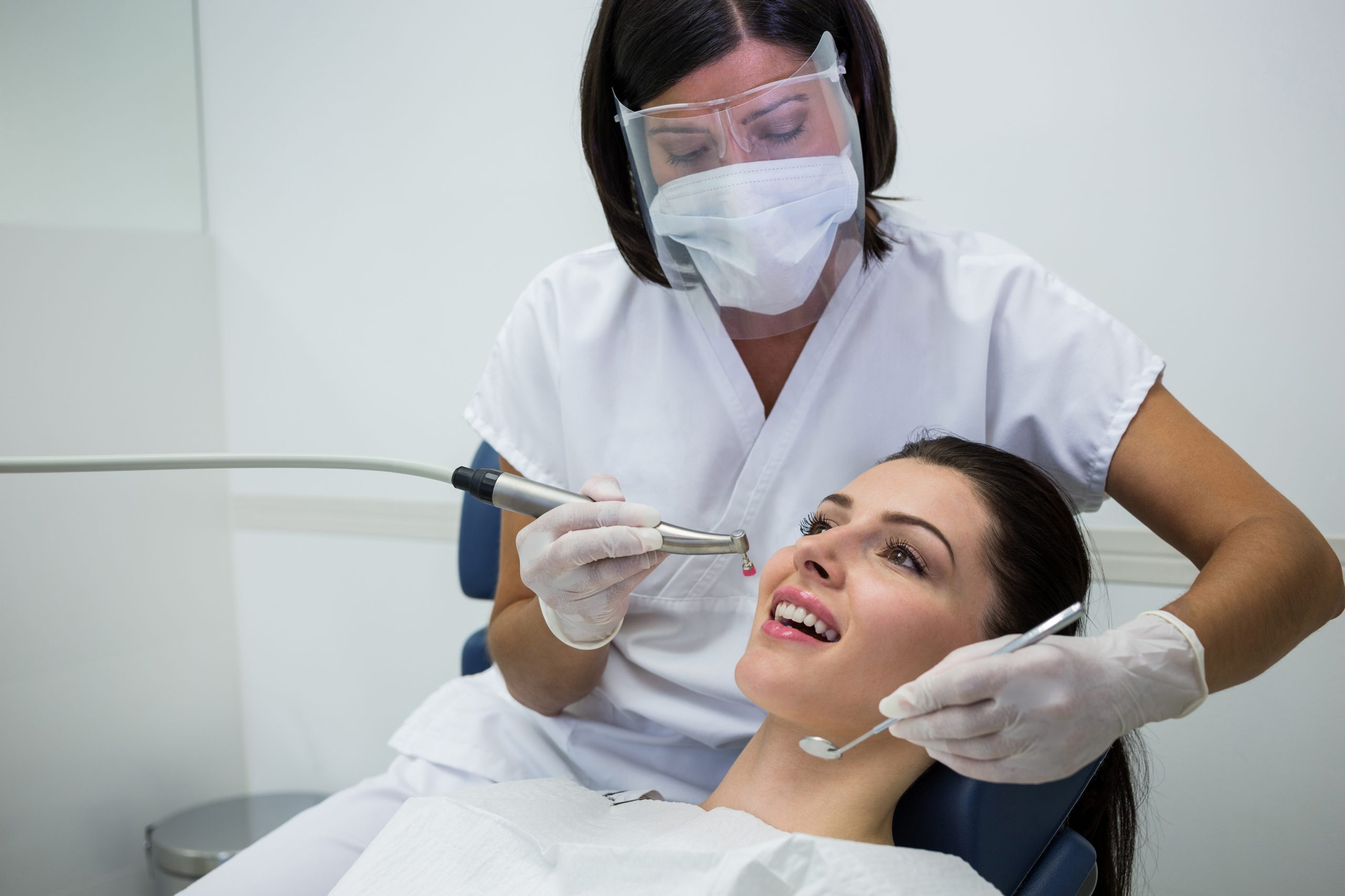 Dentouch_dentist_examining_female_patient_with_tools_restorative